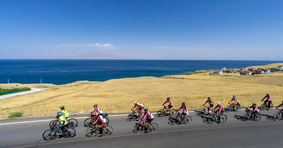 Des cyclistes s'affrontent le long d'une route côtière pittoresque avec vue sur l'océan sous un ciel bleu dégagé.